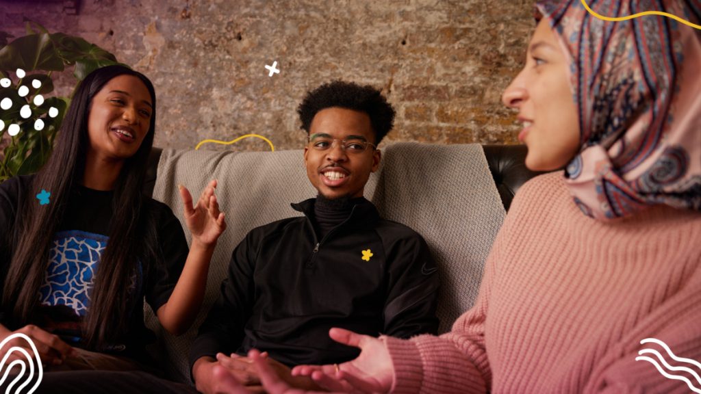Three young people sitting on a sofa in conversation