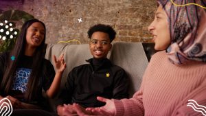 Three young people sitting on a sofa in conversation