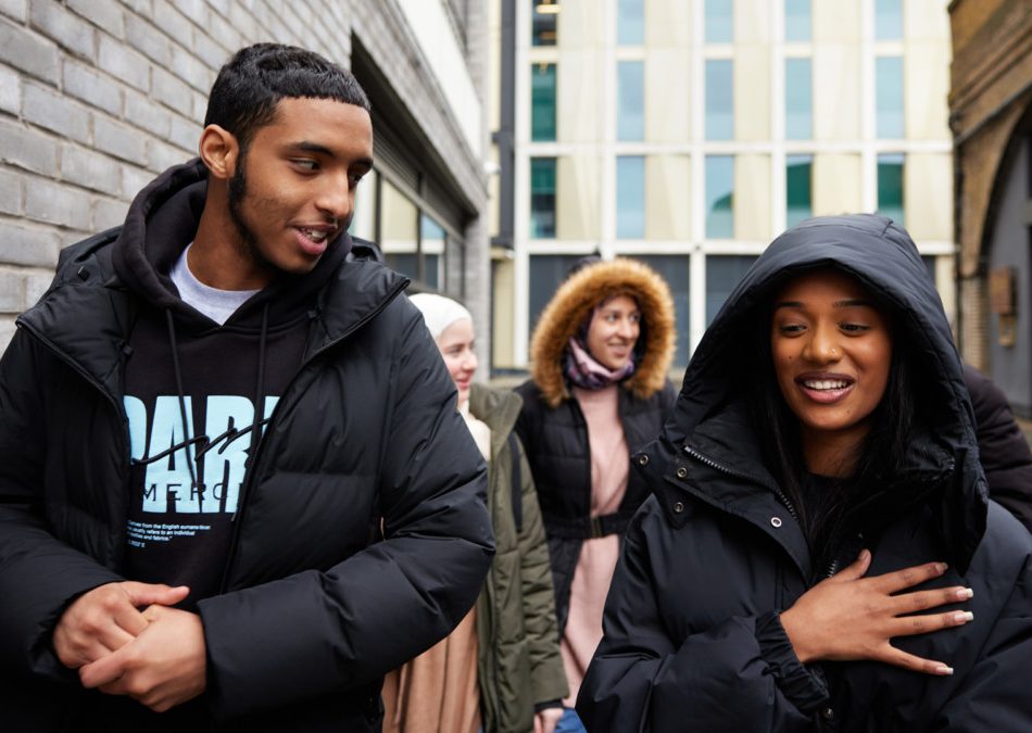 Three young people standing outdoors, talking and laughing