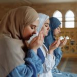 Women praying together with their hands raised